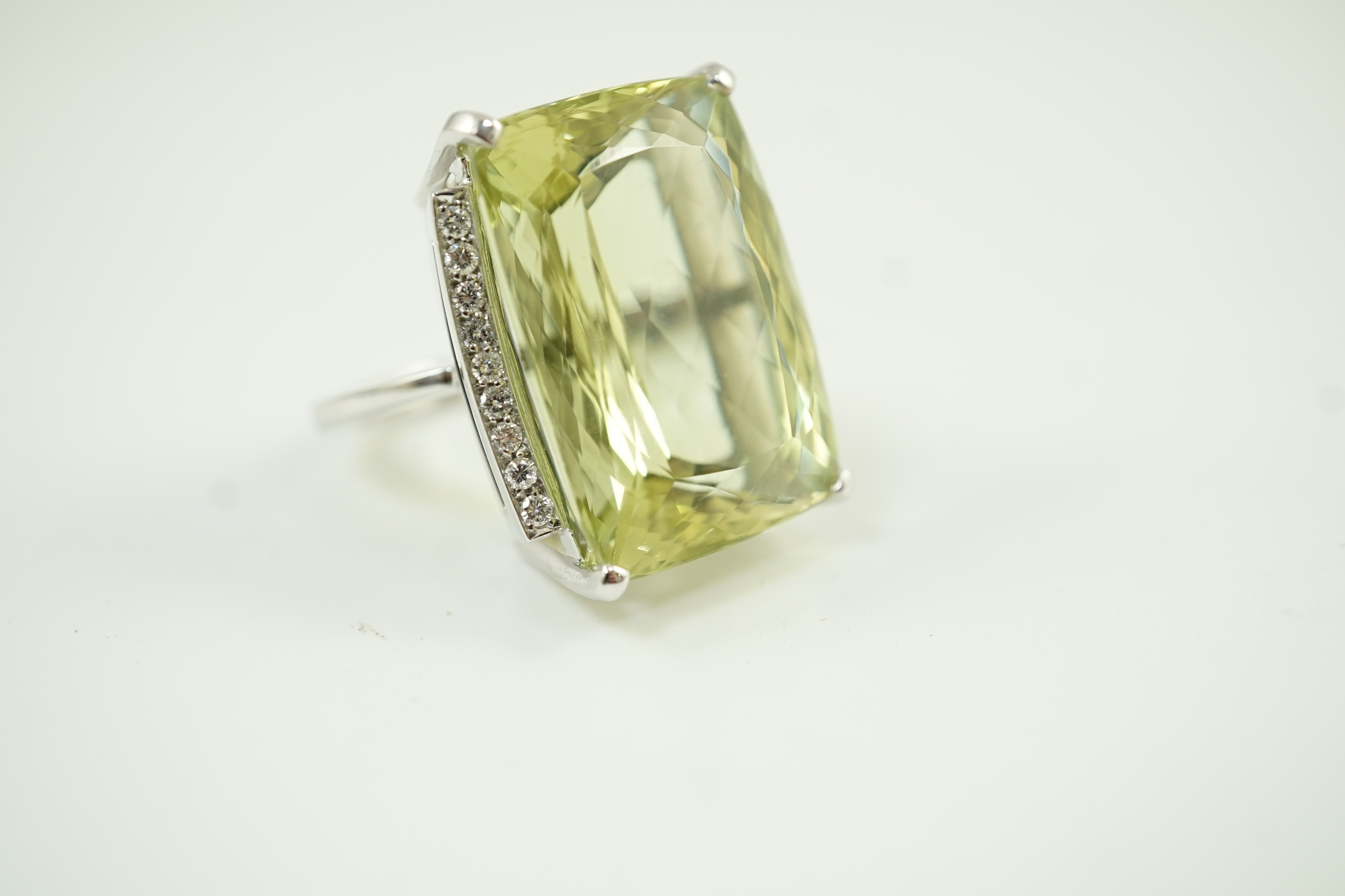 A modern white gold and shaped rectangular fancy cut pale green beryl set dress ring, with diamond chip setting